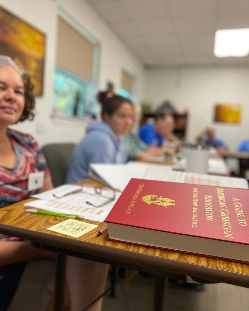 Woman student at teachers for the nations with the red books on the table at CHS