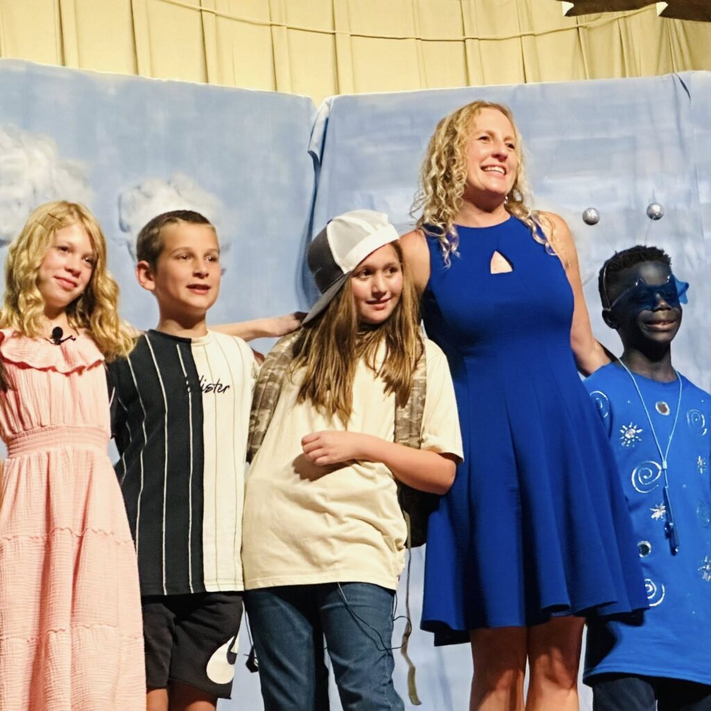 kriya thomas standing with students a production of out of this world