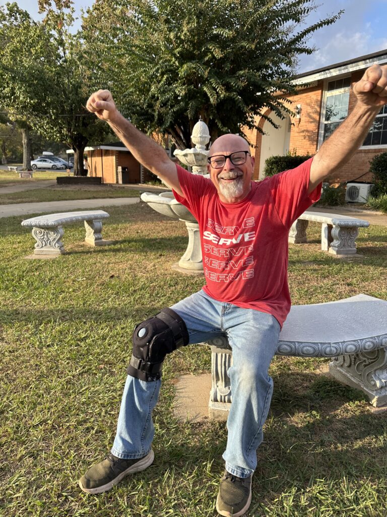 david wigent with hands raised sitting by the CHS fountain.
