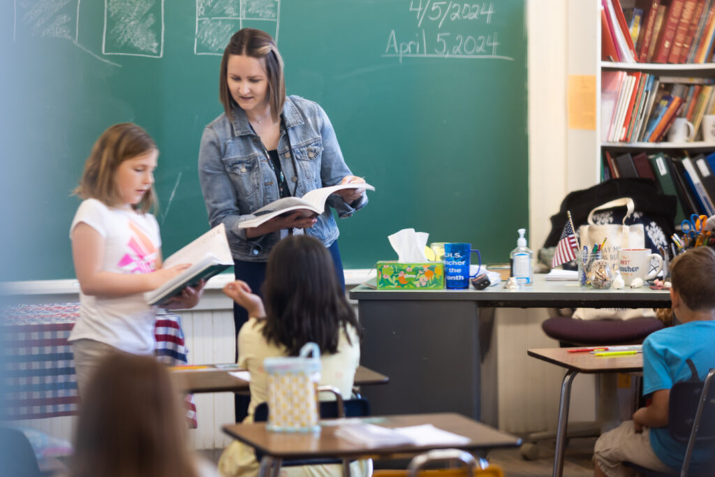 teachers for the nations student in front of class helping a young student at CHS