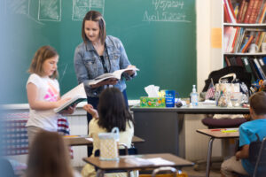 teachers for the nations student in front of class helping a young student at CHS