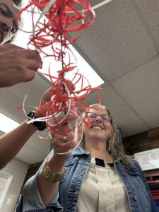 rachel holding pom pom of red and white ribbons